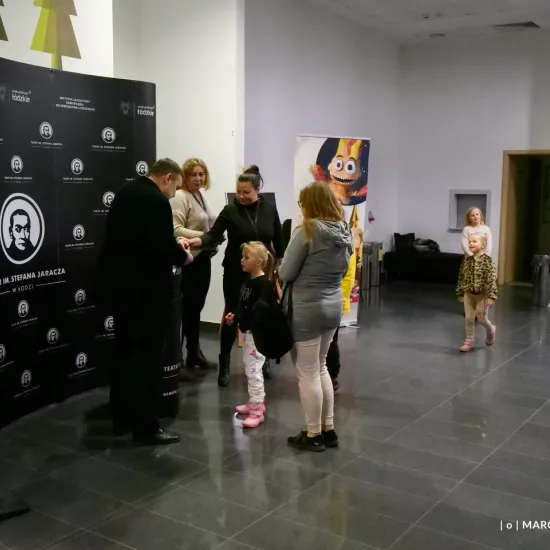 zdjęcie przedstawia widzów oczekujących na wejście na salę teatralną, na foyer w Miejskim Centrum Kultury w Bełchatowie 