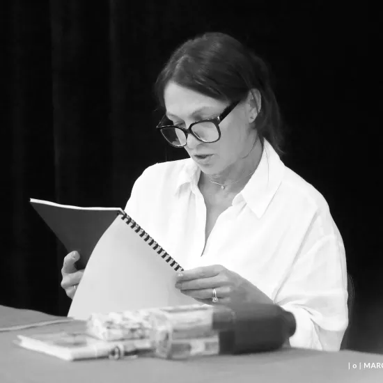 pierwsza próba spektaklu „Czas na wielki numer", na zdjęciu aktorka Monika Badowska, która siedzi przy stole i czyta egzemplarz sztuki, naz djęcie nałożony jest czarno-biały filtr, fot. Marcin Nowak